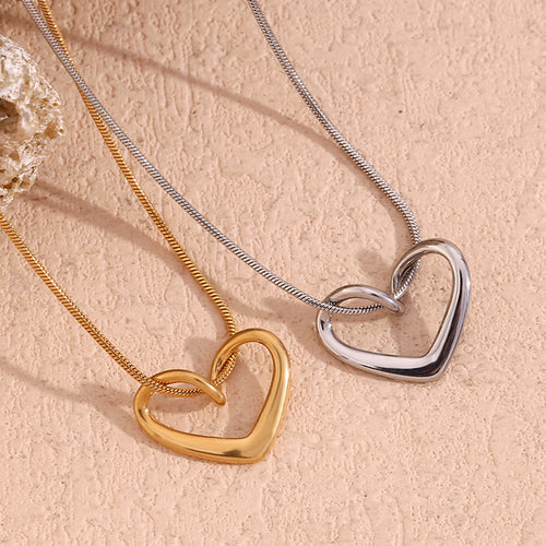 Two heart-shaped pendants on chains against a beige background