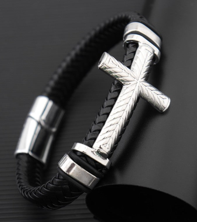 Black leather bracelet with silver cross charm on a dark background