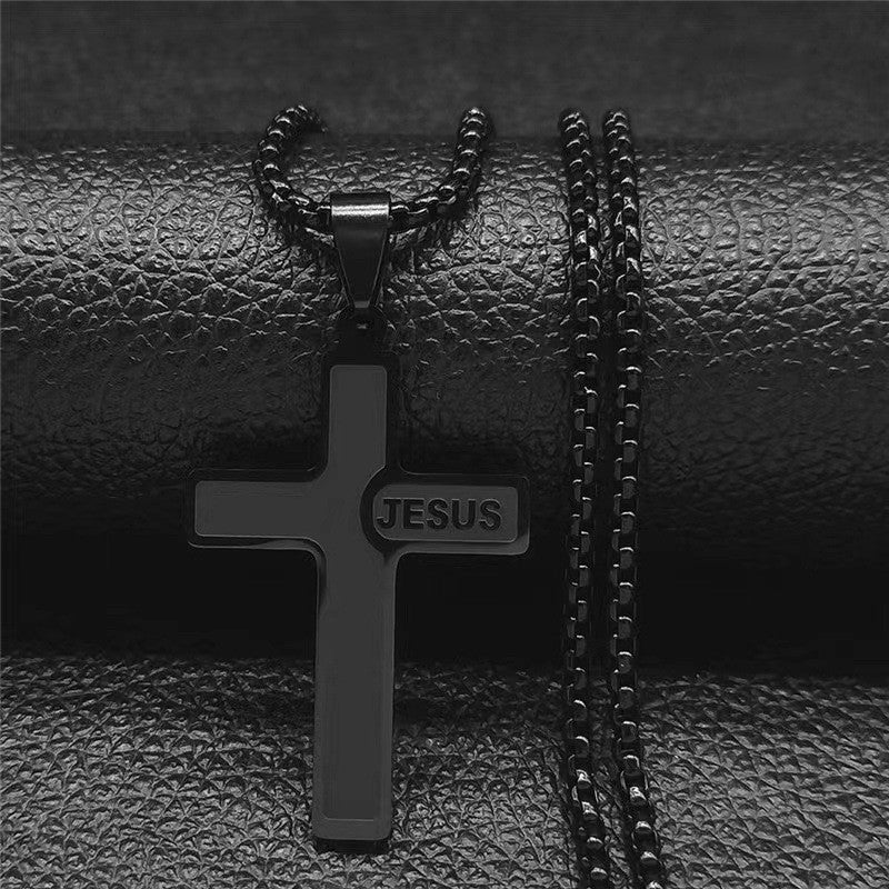 Black cross pendant with 'JESUS' engraving on a chain against a black leather background