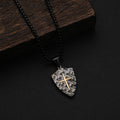 Shield-shaped pendant with a cross on a black background