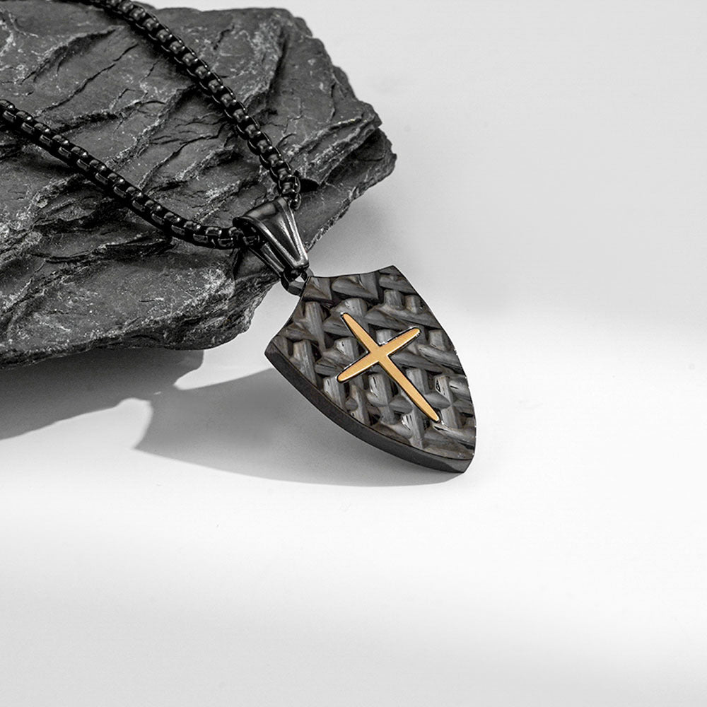 Necklace with a shield-shaped pendant featuring a gold cross on a stone surface.