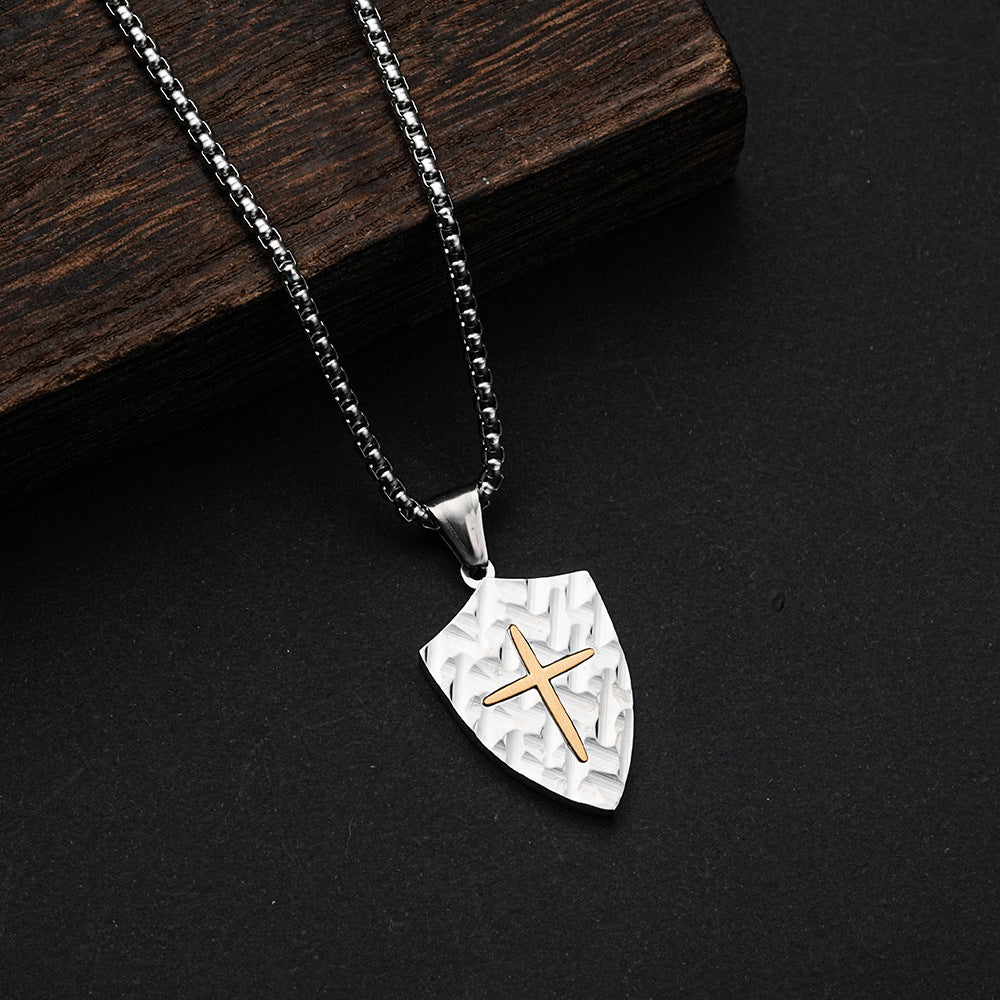 Shield-shaped pendant with a gold cross on a black background