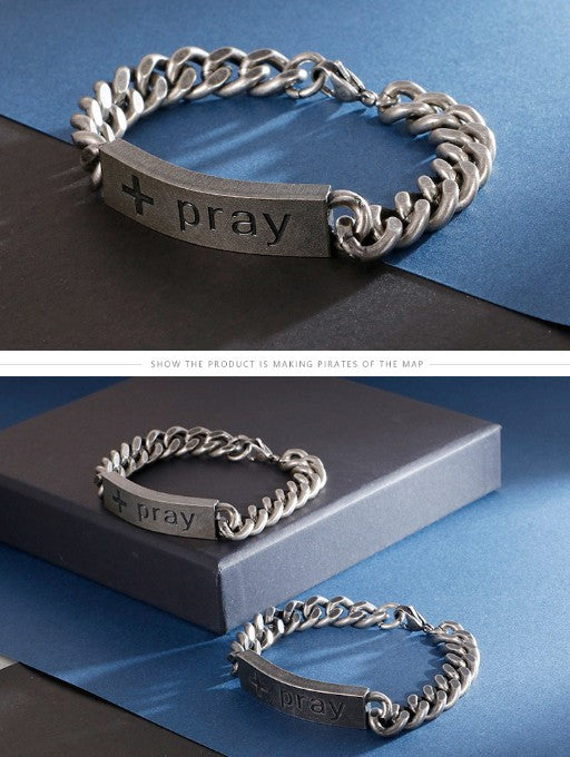 Silver chain bracelet with 'pray' engraving on a blue and black background
