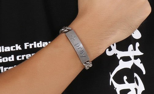 Silver bracelet with engraved text on a wrist against a black background with white text.