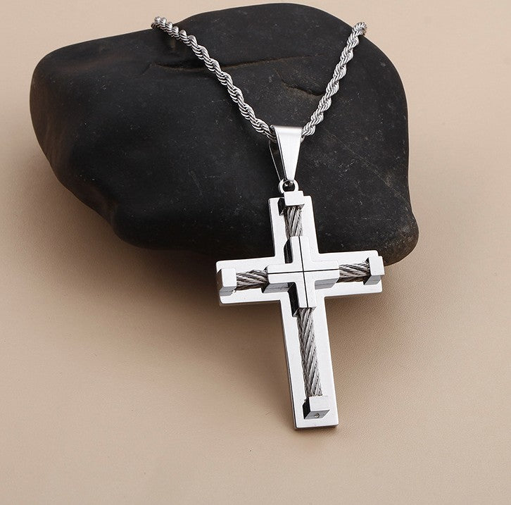 Silver cross pendant on a chain against a black stone background