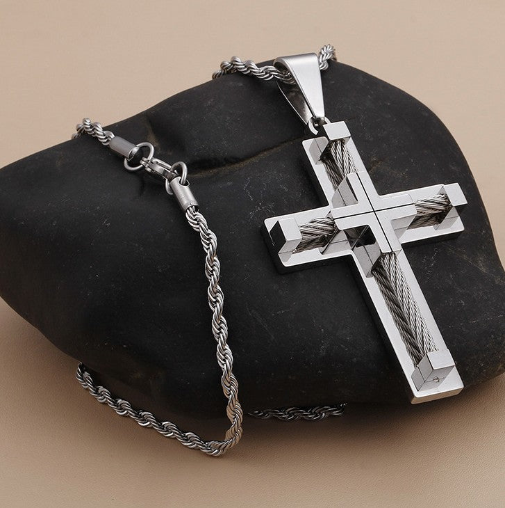 Silver cross necklace with chain on a dark stone surface
