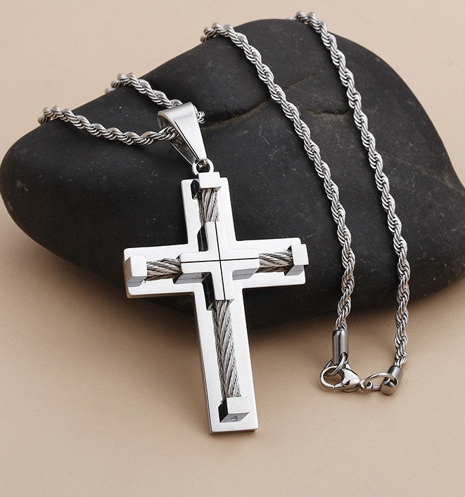 Silver cross pendant necklace on a stone surface