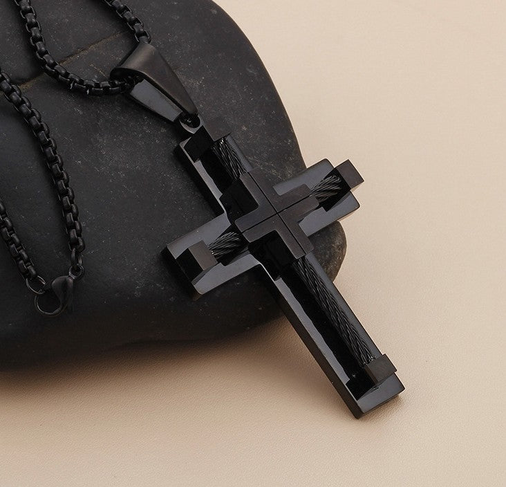 Black cross pendant necklace on a beige background