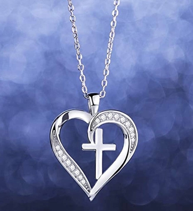 Silver heart-shaped necklace with a cross pendant on a blue blurred background