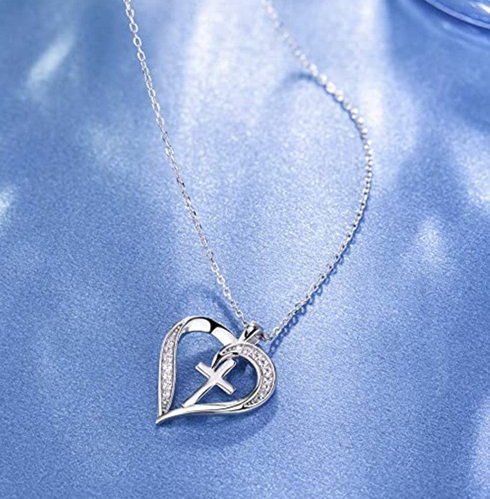 Silver heart-shaped necklace with a cross pendant on a blue background
