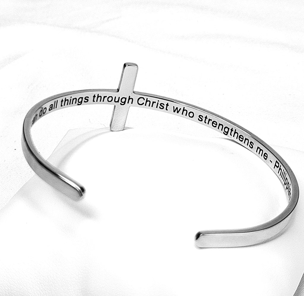 Silver bracelet with cross design and engraved text on a white background