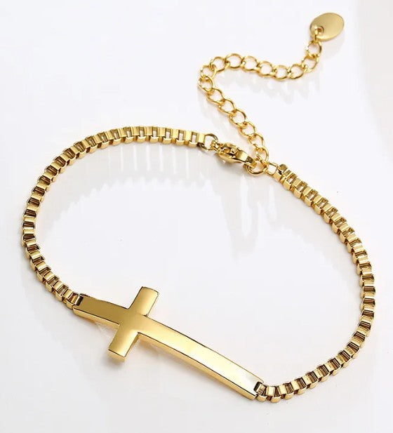 Gold bracelet with a cross charm on a white background