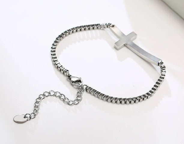 Silver bracelet with a cross pendant on a white background