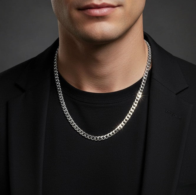 Man wearing a silver chain necklace against a dark background
