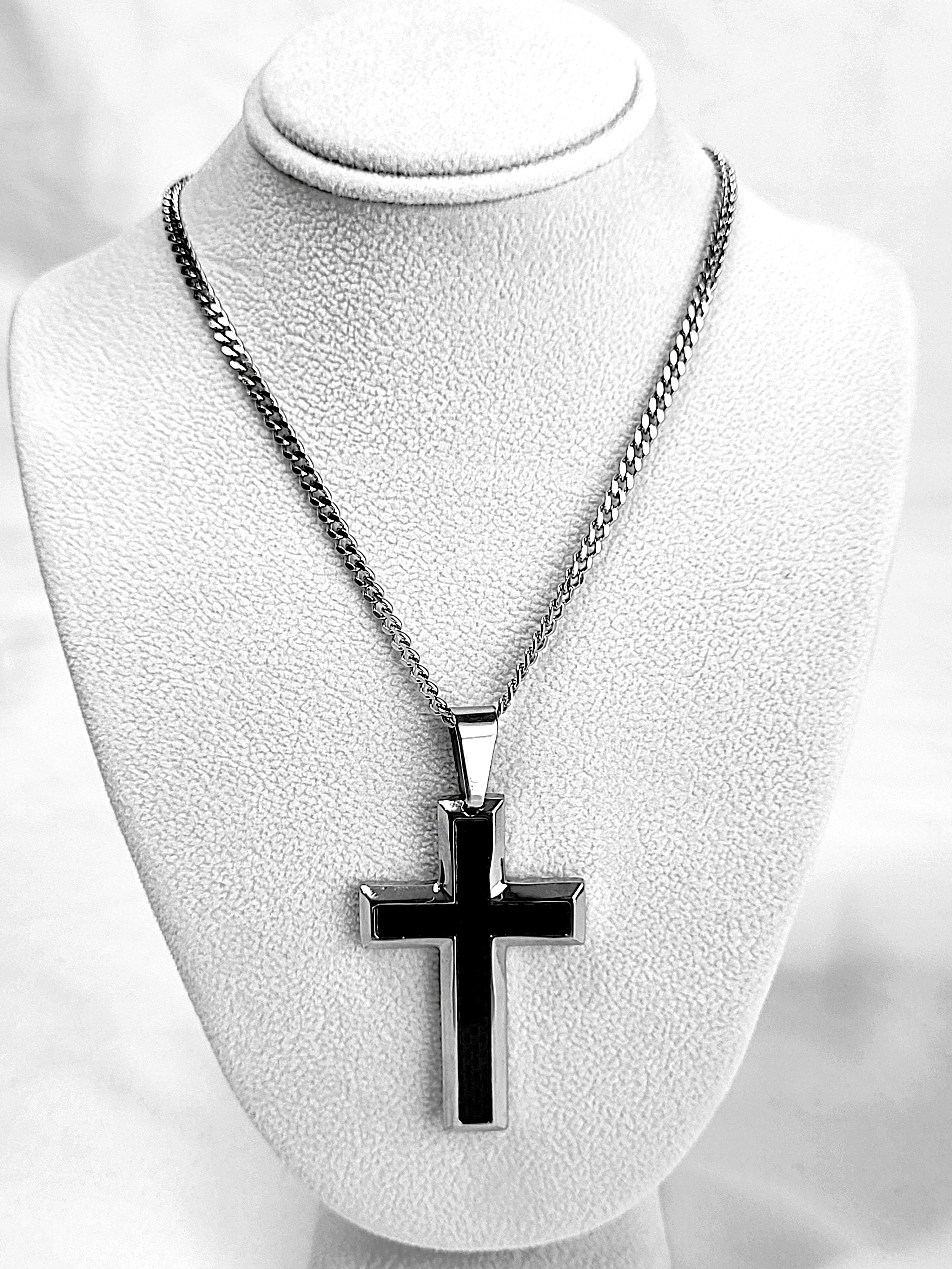 Black cross pendant on a chain necklace displayed on a mannequin bust.