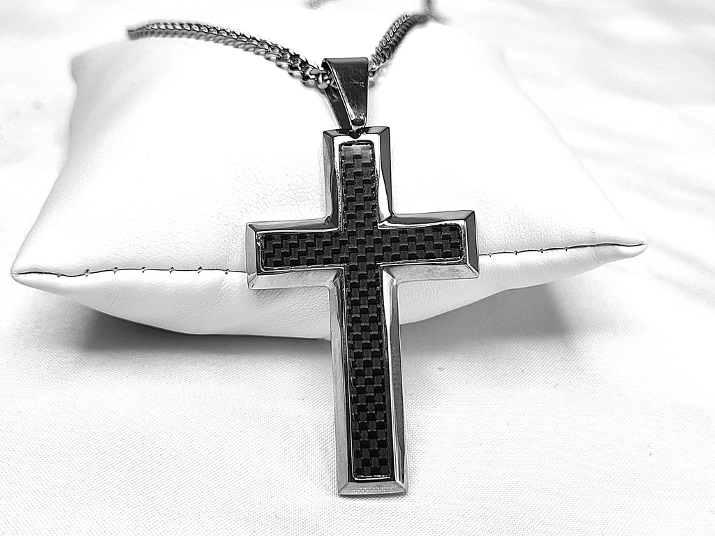 Silver cross pendant with carbon fiber pattern on a white cushion