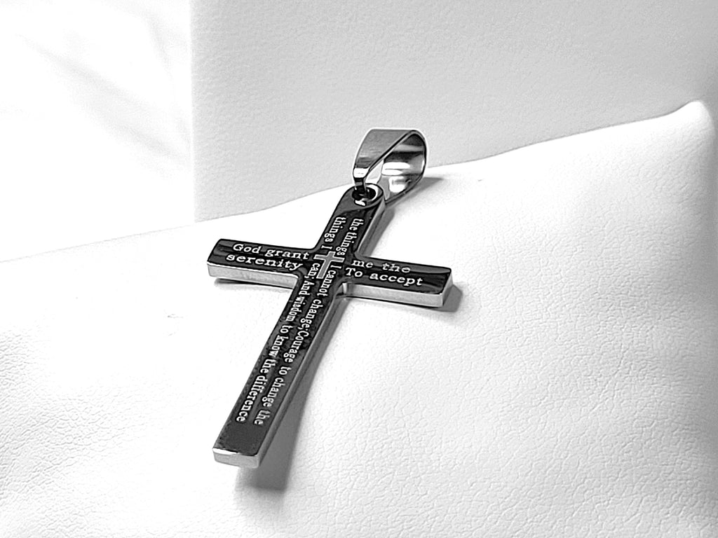 Silver cross pendant with engraved text on a white cushion