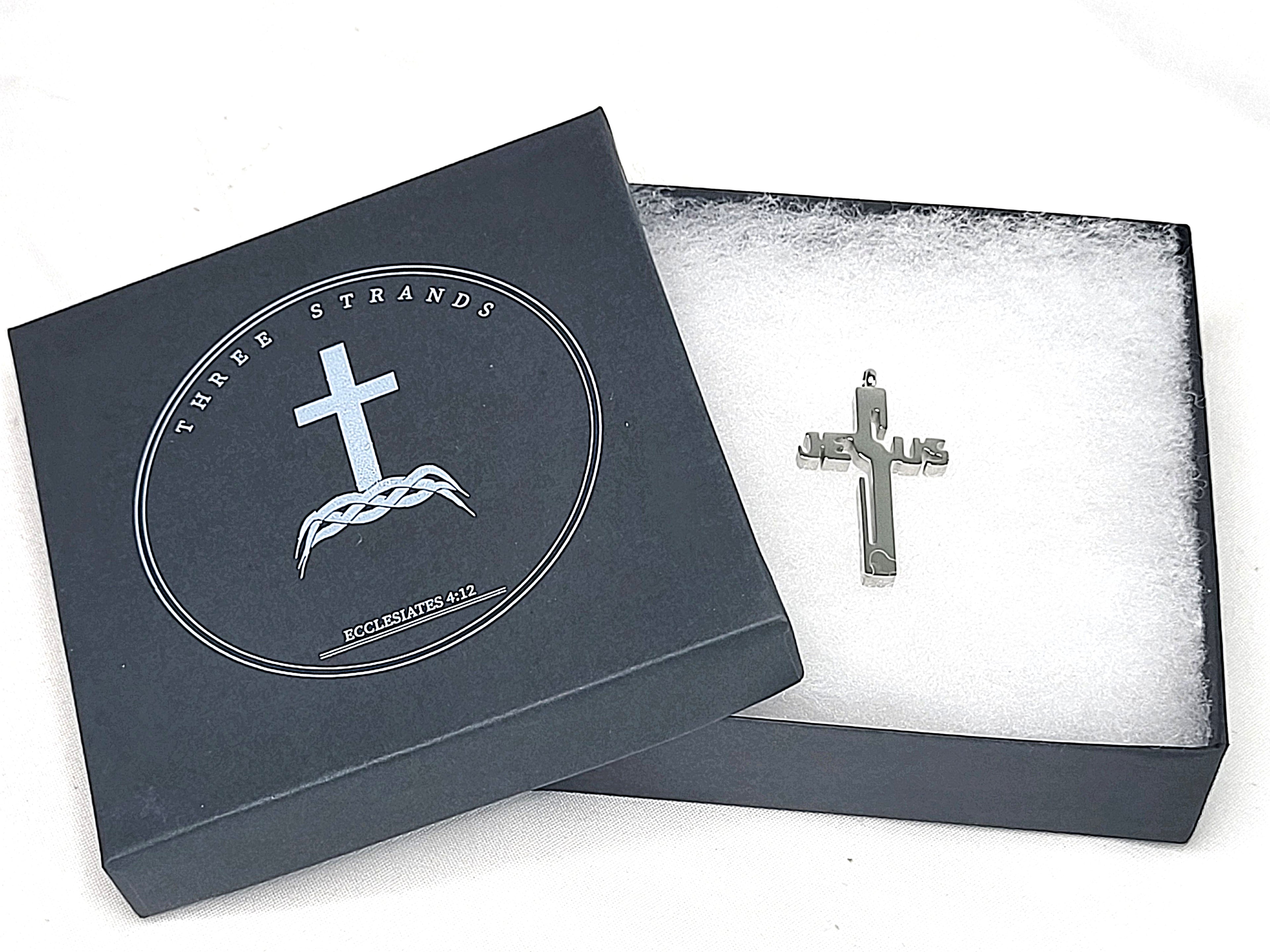 Silver cross pendant in a black jewelry box with brand logo.
