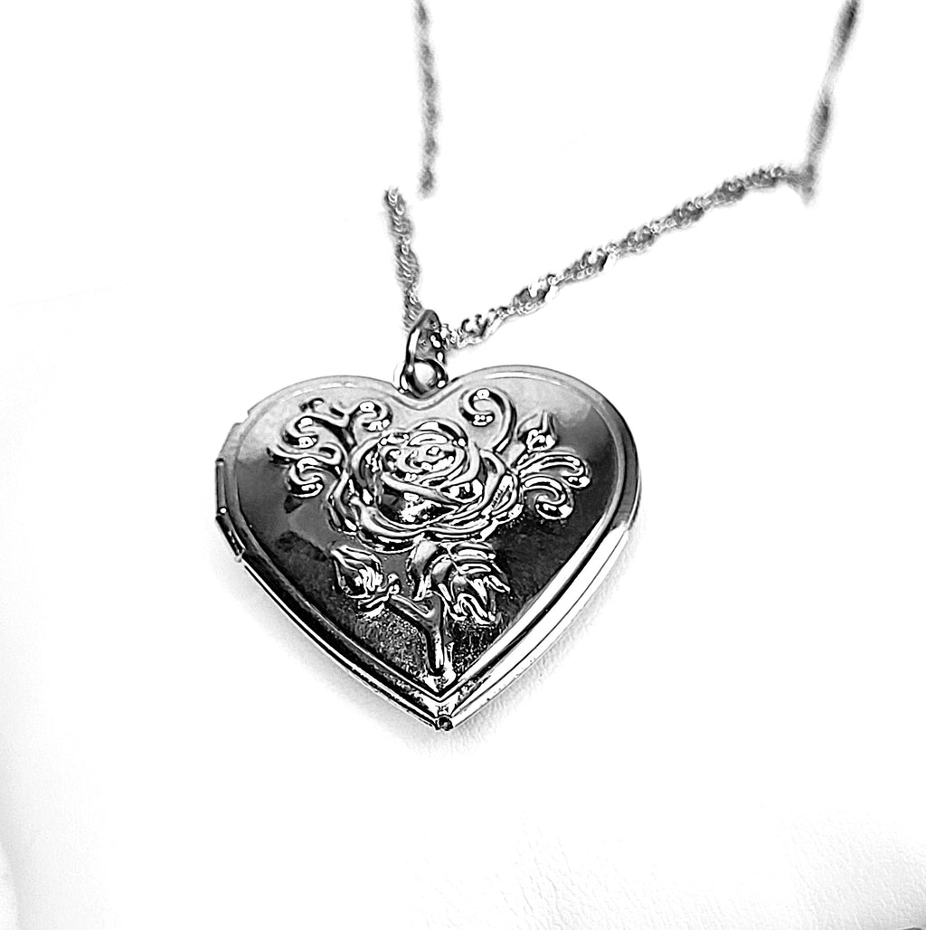 Heart-shaped silver locket with floral design on a white background