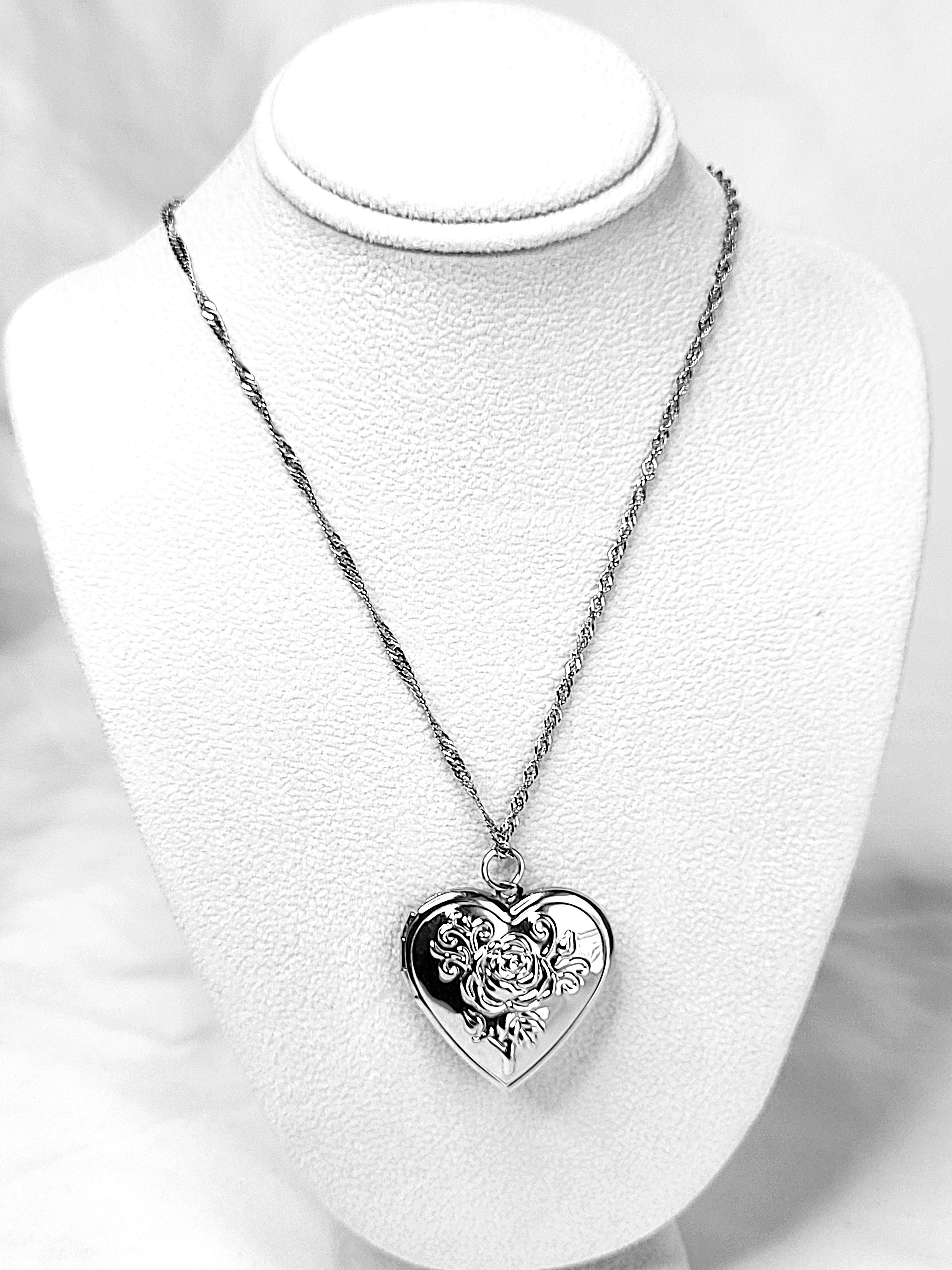 Heart-shaped silver pendant necklace on a white mannequin bust.