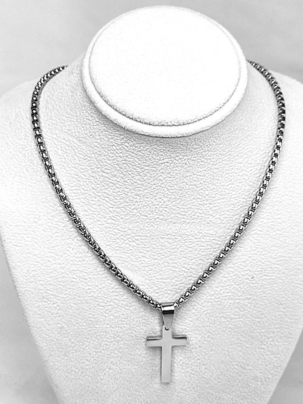 Silver cross necklace on a white mannequin bust